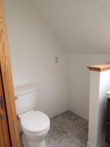 Bathroom toilet area in eaved room with gray tile